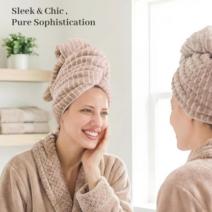 Woman wearing a taupe waffle-textured hair towel wrap twisted on her head, smiling at her reflection in a bathroom mirror. She wears a matching robe. Text reads 'Sleek & Chic, Pure Sophistication.'