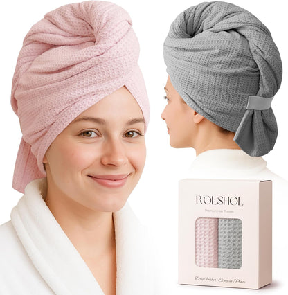 Two models wearing waffle-textured hair towel wraps: one facing forward in pink, one shown from behind in gray, both wearing white robes. A product box labeled 'ROLSHOL Premium Hair Towels' with both colors is shown in the lower right.