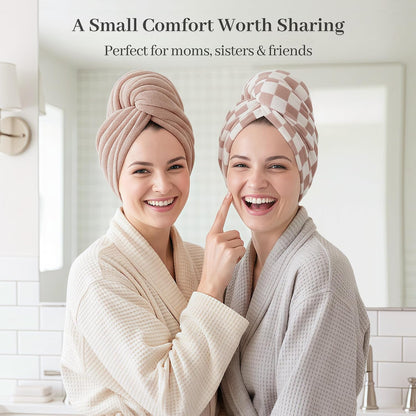 Two smiling women in waffle-weave robes wearing hair towel wraps in a bathroom setting. One wears a solid mauve wrap, the other a pink-and-white checkered wrap. Text reads: 'A Small Comfort Worth Sharing - Perfect for moms, sisters & friends'