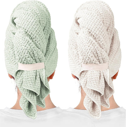 Two hair towel wraps shown from behind on a person: one in soft green and one in light beige/gray. Both feature a textured waffle-like fabric, a securing band at the back, and draped fabric hanging down.