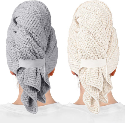 Two hair towel wraps shown from behind on models: one gray and one cream/beige. Both feature a waffle-knit texture, elastic band closure at the back, and a loose draping tail. White background.