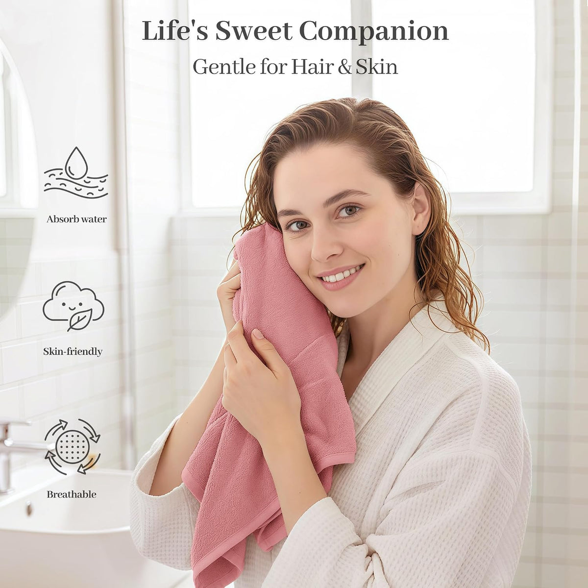 Woman in a white robe pressing a pink textured towel against her cheek, with wet hair. Text reads 'Life's Sweet Companion - Gentle for Hair & Skin' with icons for Absorb water, Skin-friendly, and Breathable.