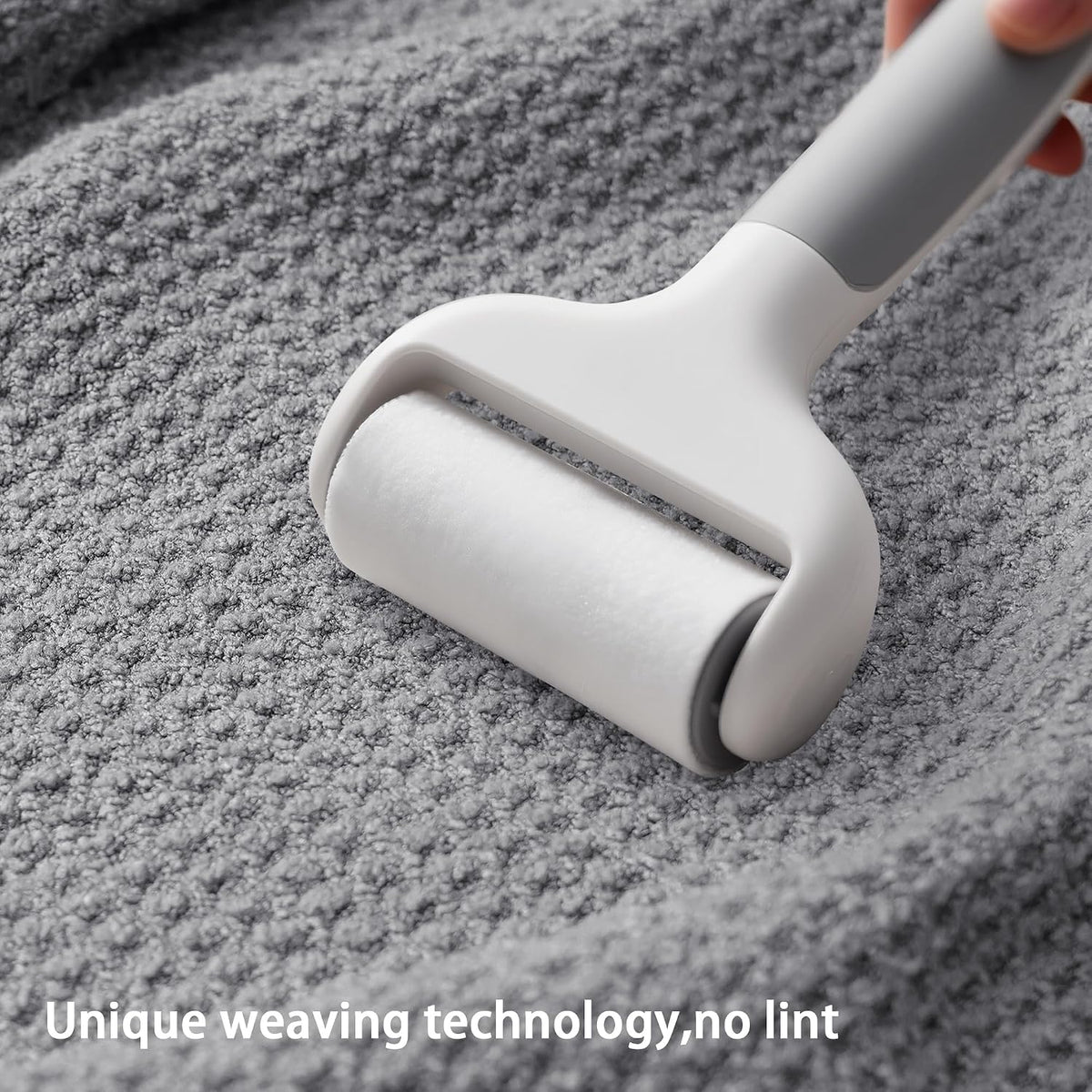 A white lint roller being pressed onto a gray textured fabric surface, shown in use from a close-up angle. Text overlay reads 'Unique weaving technology, no lint'.