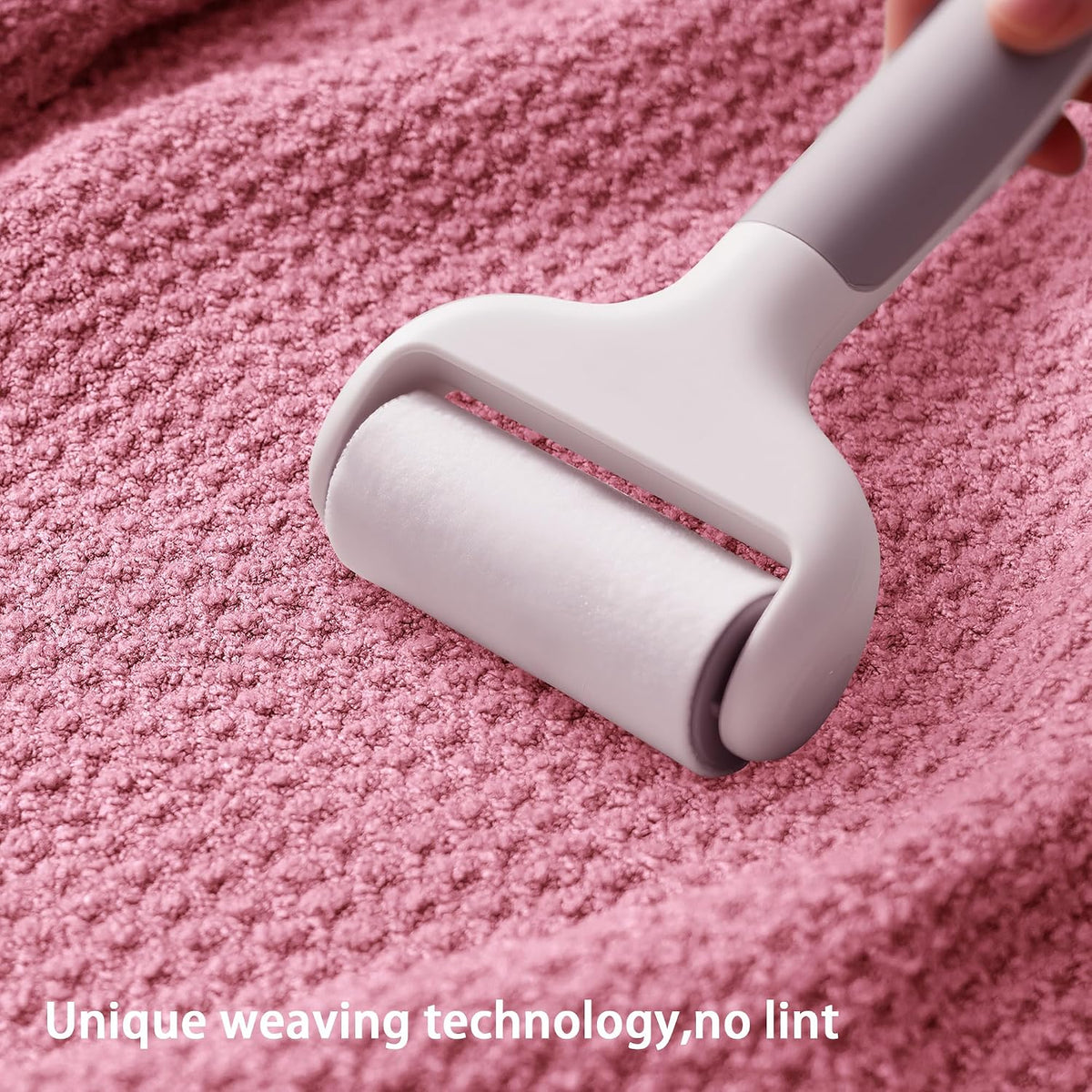 A light gray lint roller being pressed onto a textured pink waffle-weave fabric surface. Text overlay at the bottom reads 'Unique weaving technology, no lint'.