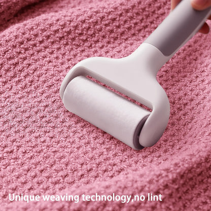 A light gray lint roller being pressed onto a textured pink waffle-weave fabric surface. Text overlay at the bottom reads 'Unique weaving technology, no lint'.