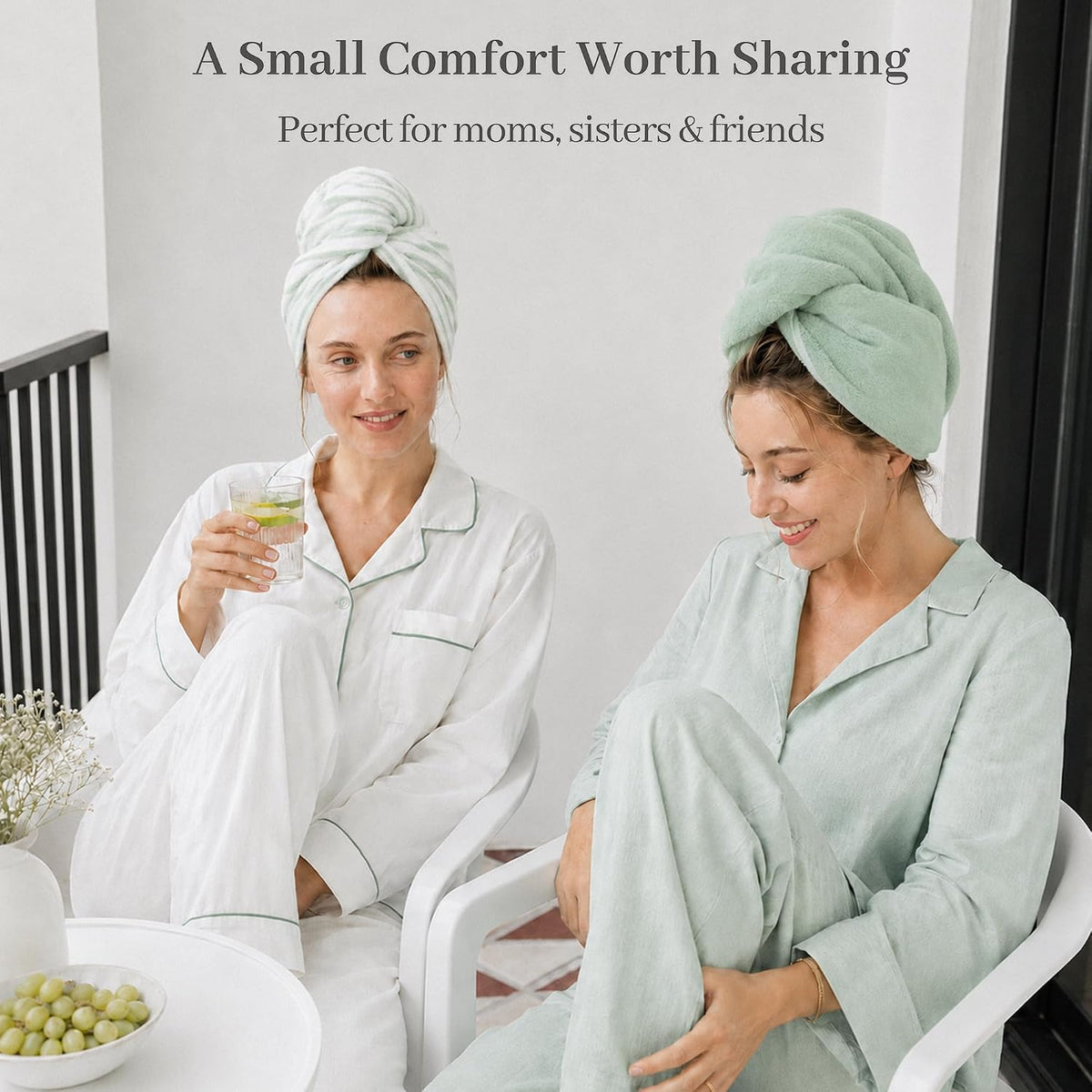 Two women in pajamas sitting on white chairs, each wearing a light green hair towel wrap twisted into a turban style. Text reads 'A Small Comfort Worth Sharing - Perfect for moms, sisters & friends.'