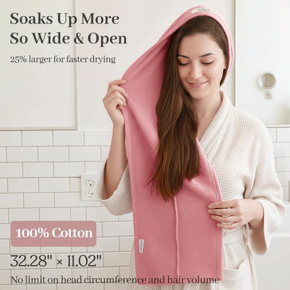 Woman in a white waffle robe using a pink cotton hair towel wrap draped over her head and long brown hair. Text states 'Soaks Up More So Wide & Open,' '25% larger for faster drying,' '100% Cotton,' and dimensions 32.28" x 11.02".